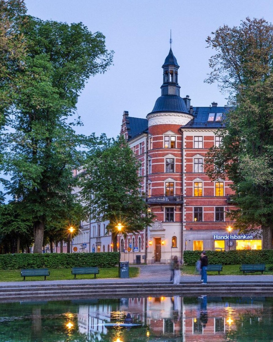Fontän i skymning framför sekelskifteshus på Karlaplan